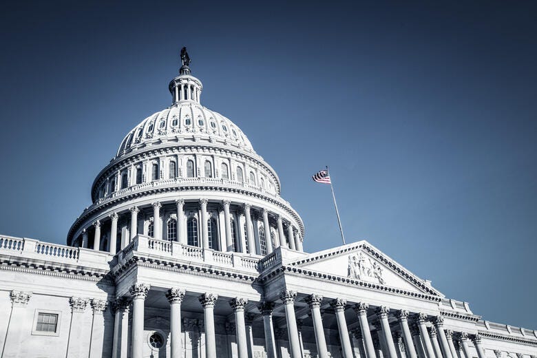 a white building with a flag on top with United States Capitol in the background