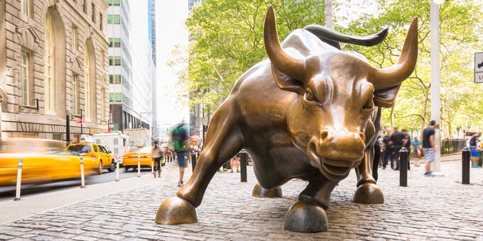 a statue of a bull on a sidewalk in a city