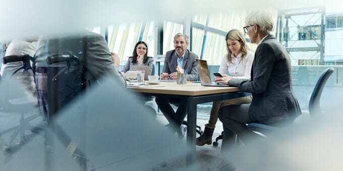 a group of people sitting around a table with laptops