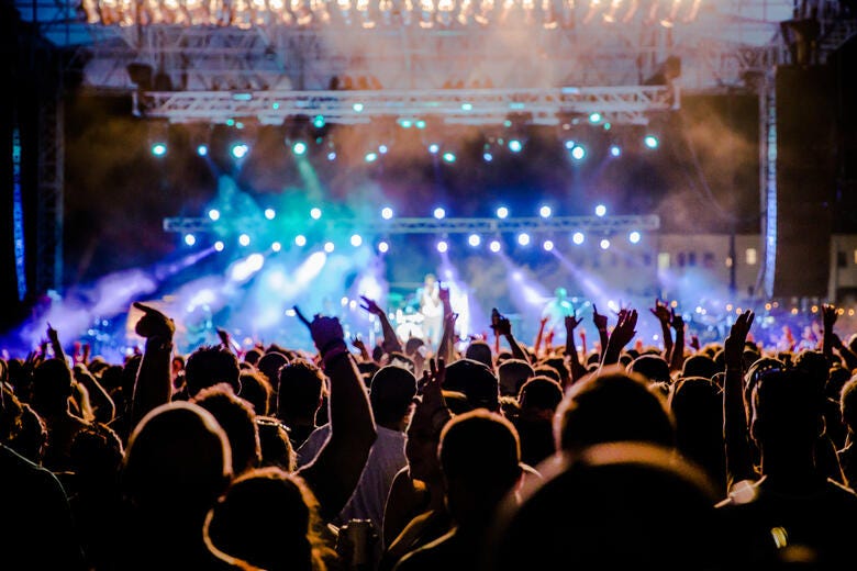 a crowd of people in front of a stage with lights