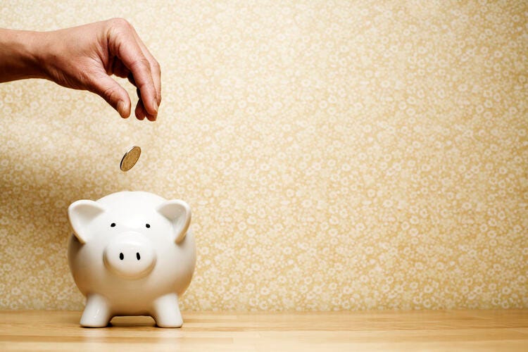 a hand touching a piggy bank